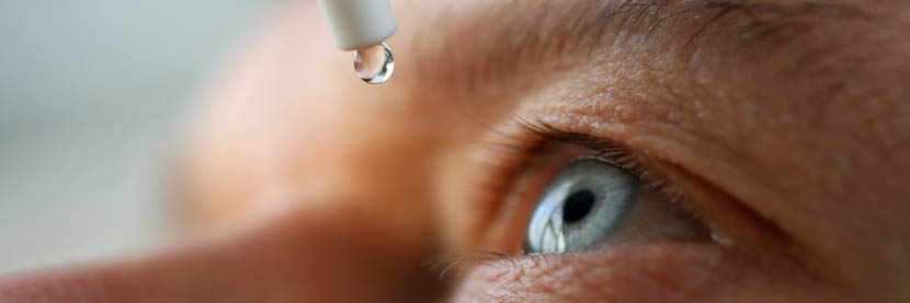 person putting eye drops into eye