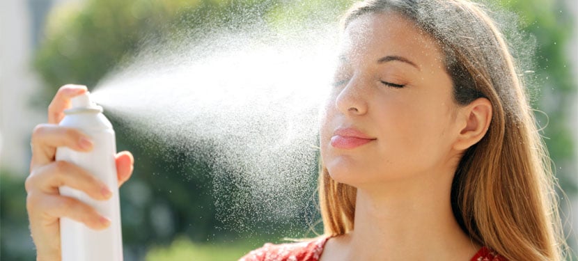 woman spraying her face with closed eyes